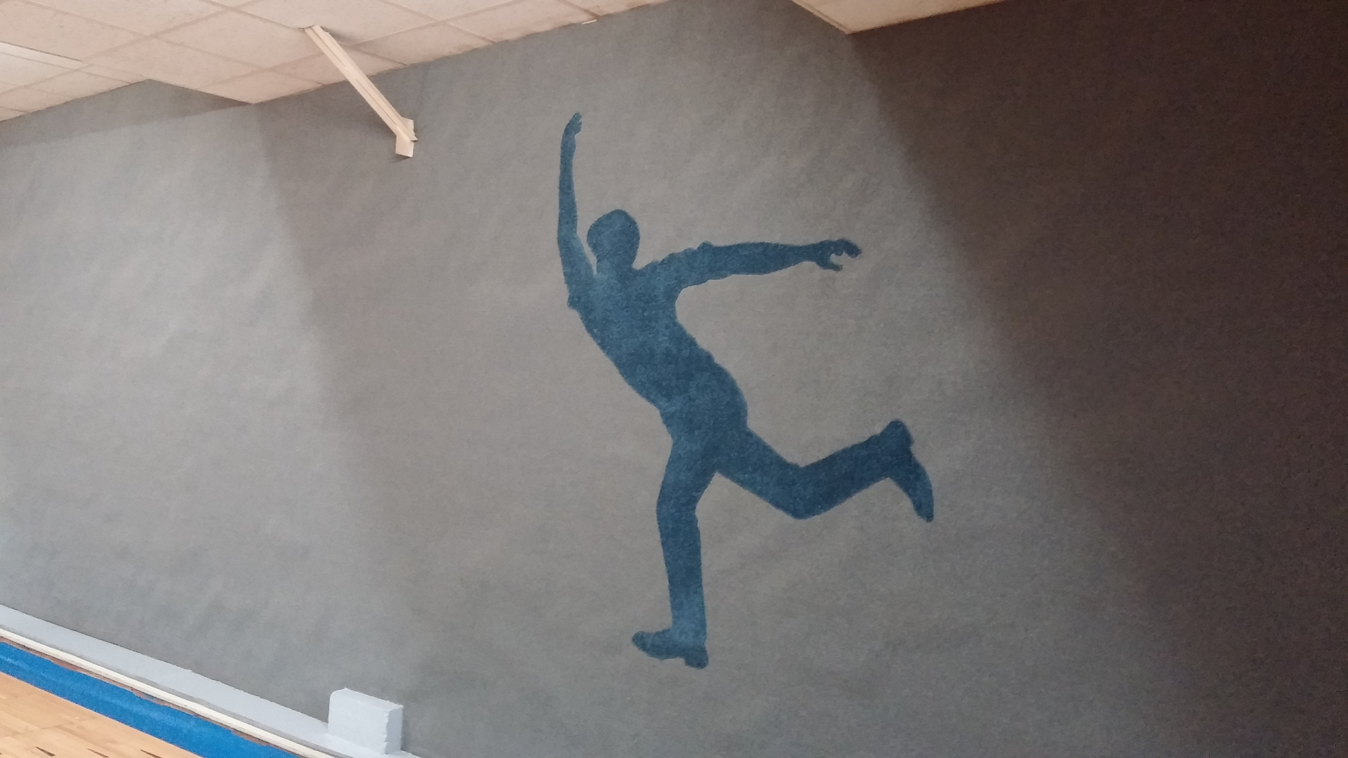 Painted bowler silhouette mural on the wall above the lanes at 281 Bowl